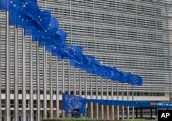 FILE - Workers adjust the EU flags in front of EU headquarters in Brussels, Belgium, June 22, 2016. Voters in the United Kingdom are taking part in a referendum that will decide whether Britain remains part of the European Union or leaves the 28-nation bloc.