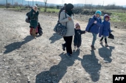 A woman and children cross the Greek-Macedonian border near the town of Gevgelija, Feb. 25, 2016. Merkel has said an EU solution cannot be done in a way that abandons Greece.