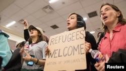 A woman holds a sign during a protest against the travel ban imposed by U.S. President Donald Trump's executive order, at Dallas/Fort Worth International Airport in Dallas, Texas, Jan. 28, 2017.
