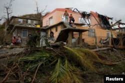 People rest outside a damaged house after the area was hit by Hurricane Maria in Yabucoa, Puerto Rico, Sept. 22, 2017.