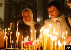 People light candles inside an Orthodox church in St.Petersburg during a day of national mourning for the plane crash victims, Russia, Nov. 1, 2015.