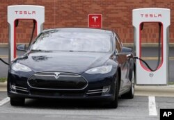 FILE - A Telsa car recharges at a Tesla charging station in Charlotte, N.C., June 24, 2017.