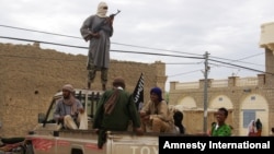 Fighters from Islamist group Ansar Dine stand guard as they prepare to publicly lash a member of the Islamic Police found guilty of adultery, in Timbuktu, Mali. (Aug 31, 2012 file photo)