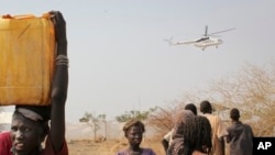 In this photo taken Wednesday, Feb. 26, 2014, a displaced South Sudanese woman carries a plastic jerry can with water in the United Nations camp that has become home to thousands of displaced people in Malakal, South Sudan. (AP Photo/Ilya Gridneff)