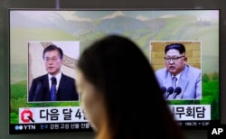 FILE - A visitor walks by a TV screen showing file footage of South Korean President Moon Jae-in, left, and North Korean leader Kim Jong Un, right, during a news program at the Seoul Railway Station in Seoul, South Korea, March 29, 2018.