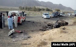 Volunteers stand near the wreckage of a destroyed vehicle, in which Mullah Akhtar Mansour was allegedly traveling in the Ahmed Wal area in Baluchistan province of Pakistan, near the Afghanistan border, May 21, 2016.