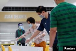 Pemilih memberikan suara mereka di TPS di Singapura pada 10 Juli 2020. (Foto: REUTERS/Edgar Su)