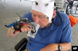 Cuplikan video tidak bertanggal ini menunjukan seorang pasien yang menggunakan lengan robot untuk minum dari gelas di Badalona, Spanyol.