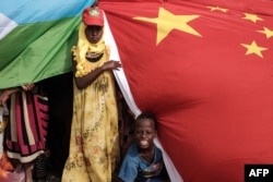 People hold Chinese and Djiboutian national flags as they wait for the arrival of Djibouti’s president, Ismaïl Omar Guelleh, before the launching ceremony of new 1,000-unit housing construction project in Djibouti, July 4, 2018. The project is financially supported by China Merchant, the operation partner of newly inaugurated Djibouti International Free-Trade Zone.