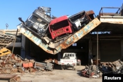Damaged vehicles sit on the damaged roof of a car service center in the Ramousah area southwest of Aleppo, Syria, Aug. 2, 2016.