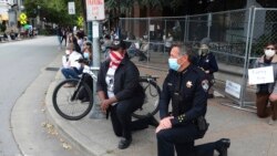 Le chef de police Andy Mills, à droite, et le maire de Santa Cruz Justin Cummings, au centre, mettent un genou à terre sur Pacific Avenue au centre-ville de Santa Cruz en Californie le 30 mai 2020 pour honorer la mémoire de George Floyd.