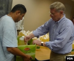 Relawan dari gereja membantu membagikan minyak dan beras bagi warga yang datang untuk bahan pangan gratis.