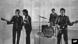 The Beatles are seen performing, date unknown. From left to right: Paul McCartney, George Harrison, Ringo Starr, and John Lennon.