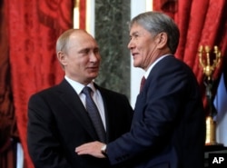 FILE - Russian President Vladimir Putin, left, welcomes Kyrgyzstan's President Almazbek Atambayev prior to a meeting of CSTO (Collective Security Treaty Organization) at the Kremlin, Moscow, Russia, Dec. 23, 2014.