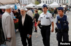 FILE - Belgian police officers Ann Vercammen (R) and Tarek Chatt patrol at a market in the Brussels district of Molenbeek, Belgium, Aug. 18, 2016.