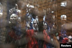 Muslim Brotherhood's Supreme Guide Mohamed Badie (C) waves with the Rabaa sign, symbolizing support for the Muslim Brotherhood, with other brotherhood members at a court in the outskirts of Cairo, May 16, 2015.