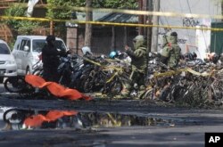 Members of a police bomb squad inspect the wreckage of motorcycles where an explosion went off outside a church in Surabaya, East Java, Indonesia, May 13, 2018.