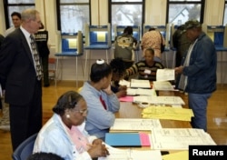 FILE - John Spindler, a lawyer representing the Republican National Committee, watches as poll workers issue a ballot to Tommie Rash, right, at Hopkins Street School on the north side of Milwaukee, Wis., Nov. 2, 2004.