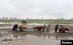 FILE - Relatives carry the bodies of civilians killed in airstrikes during a battle between Iraqi forces and Islamic State militants in Mosul, Iraq, March 17, 2017.
