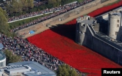 FILE - Crowds gather to see the red ceramic poppies that form part of the art installation "Blood Swept Lands and Seas of Red" at the Tower of London in London, Oct. 27, 2014.