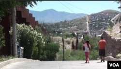 Two kids by the border wall in Nogales, Mexico. (G. Flakus/VOA)
