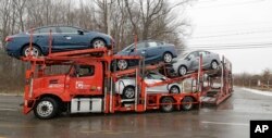 FILE - An auto transport truck full of new cars drives out of the General Motors Lordstown plant, Nov. 27, 2018.