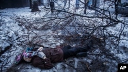 FILE - A person walks near the body of a man lying near a bus stop that was damaged in shelling in Donetsk, eastern Ukraine, Jan. 20, 2015. An estimated 9,000 people have died in the conflict in eastern Ukraine since April of 2014.