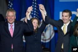 FILE - Virginia's governor-elect, Ralph Northam, right celebrates his election win with Virginia Governor Terry McAuliffe and his wife, Dorothy, in Fairfax, Va., Nov. 7, 2017.