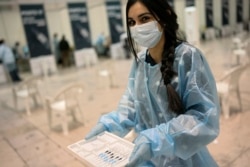 Nurse Carolina carries doses of the Pfizer vaccine against COVID-19 on the first day of a new vaccination center in Lisbon, Portugal, Dec. 1, 2021.