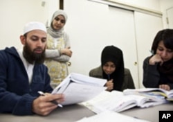 Students (from left to right) Waqas Ahmed, Sifat Reazi and Armaan Siddiqi consult with teacher Souhad Zendah (standing).