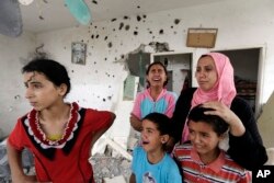 Palestinian Salwa Shabat, right, accompanied by some of her children, from left to right, Amira, Huda, top, Ahmed and Anas, weep as they inspect the damage upon returning to the family house, destroyed by Israeli strikes in the town of Beit Hanoun.