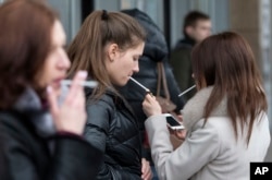 Women smoke cigarettes at a shopping center in Moscow, Russia, Tuesday, Feb. 12, 2013.