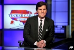 FILE - Tucker Carlson, host of "Tucker Carlson Tonight," poses for photos in a Fox News Channel studio, in New York, March 2, 2017.