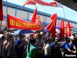 FILE - Workers wave Vietnamese national flags during an anti-China protest at a Chinese shoe factory in Vietnam's northern Thai Binh province, May 14, 2014. Thousands of Vietnamese set fire to foreign factories and rampaged in industrial zones in the south of the country in an angry reaction to Chinese oil drilling in a part of the South China Sea claimed by Vietnam, officials said.