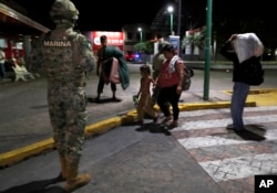 FILE - A Mexican marine stands by as camping migrant families are evicted from a park in Tapachula, Mexico, May 29, 2019.