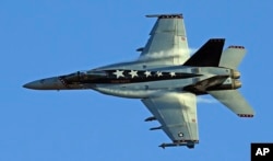 FILE - Vapor trails are seen forming on an F/A-18E Super Hornet from Naval Air Weapons Station China Lake over Death Valley National Park, California, Feb. 28, 2017.