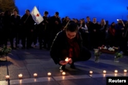 A woman places a candle with others at the Place Saint-Michel the day after Notre-Dame Cathedral suffered heavy damage from a massive fire that devastated large parts of the gothic structure in Paris, France, April 16, 2019.