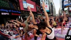Fitness experts recommend mixing up running with an exercise like yoga that is easier on the body. Here, New Yorkers do yoga in Times Square, June 2014. (AP PHOTO)