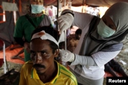 A migrant, who arrived in Indonesia by boat Friday along with other Bangladeshi and Rohingya migrants, receives medical treatment in Kuala Langsa, in Indonesia's Aceh province, May 16, 2015.