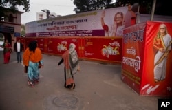 Devotees walk past banners of Bangladeshi Prime Minister Sheikh Hasina near Dhakeshwari Temple in Dhaka, Bangladesh, Jan. 1, 2019.