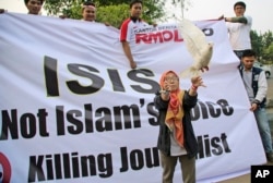 FILE - A woman releases a dove as a symbol of peace during a rally against the Islamic State group, in Jakarta, Indonesia, Sept. 5, 2014.