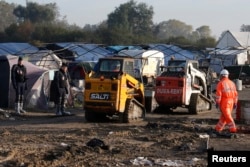 French CRS riot police secure the are as workmen and heavy machinery continue to tear down makeshift shelters and tents in the "Jungle" during the dismantlement of the camp in Calais, France, Oct. 27, 2016.