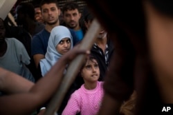 FILE - Migrants and refugees wait to leave the Golfo Azzurro rescue vessel as they arrive at the port of Pozzallo, south of Sicily, Italy, with hundreds of migrants aboard, rescued by members of Proactive Open Arms NGO, June 17, 2017.