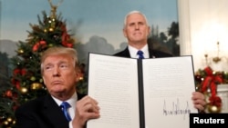 US President Donald Trump holds up a signed memorandum after he delivered a statement on Jerusalem from the Diplomatic Reception Room of the White House in Washington, DC on December 6, 2017 as US Vice President Mike Pence looks on. (Saul Loeb/AFP)
