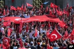 FILE - Turkish citizens wave their national flags as they protest against the military coup outside Turkey's parliament near the Turkish military headquarters in Ankara, Turkey, July 16, 2016.