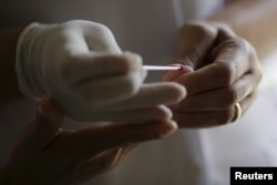 FILE - A nurse prepares an emergency test to diagnose dengue at a medical care unit of Dengue in the Sao Sebastiao neighborhood of Brasilia, Brazil, Feb. 19, 2016.
