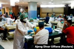 Seorang pedagang menerima dosis vaksin Sinovac Biotech China untuk COVID-19 di Pasar Tanah Abang, 17 Februari 2021. (Foto: REUTERS/Ajeng Dinar Ulfiana)