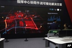 FILE - A visitor is briefed on a screen demonstrating city level surveillance at Security China 2018 expo in Beijing, Oct. 23, 2018.