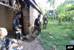 FILE - Police and soldiers take up positions as they engage with the Abu Sayyaf group in the village of Napo, Inabanga town, Bohol province, in the central Philippines, April 11, 2017.