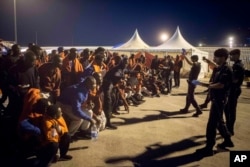 FILE - A group of migrants react in front of Spanish Police officers at the port of Algeciras, southern Spain, after being rescued by Spain's Maritime Rescue Service in the Strait of Gibraltar, July 31, 2018.